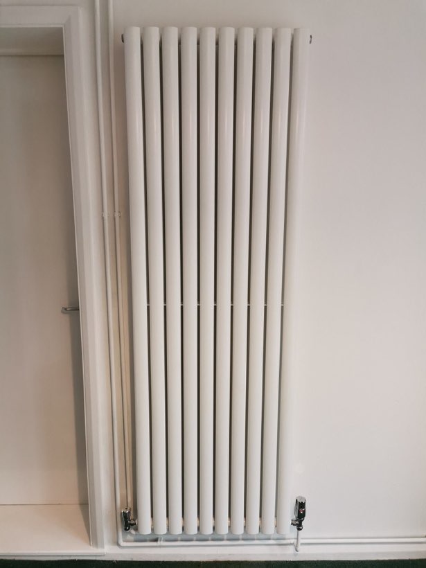 White vertical column radiator fitted beside a doorway